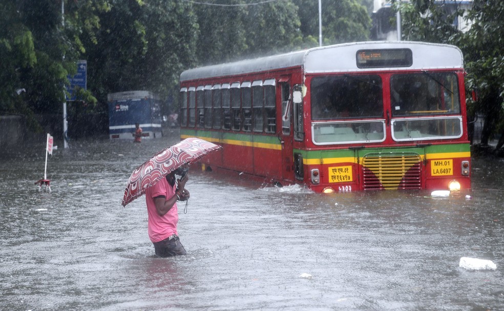 Homem caminha por rua inundada durante fortes chuvas em Mumbai, na Índia, em 9 de junho de 2021 — Foto: Rafiq Maqbool/AP