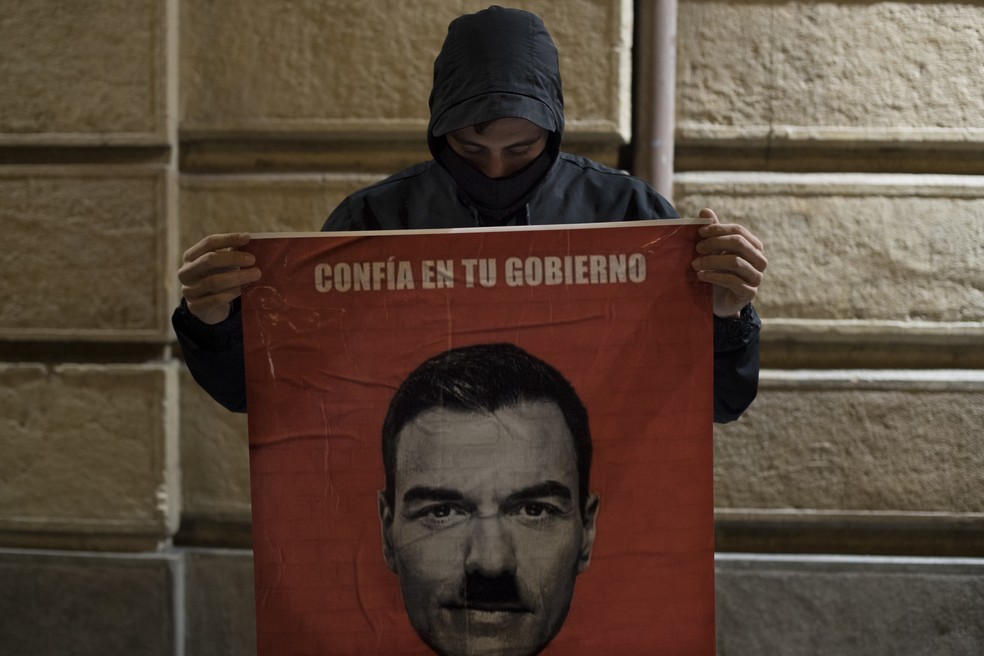 Manifestante segura cartaz com montagem de Pedro Sánchez, primeiro-ministro espanhol, usando um bigode parecido com o de Hitler, ditador nazista — Foto: Josep Lago/AFP