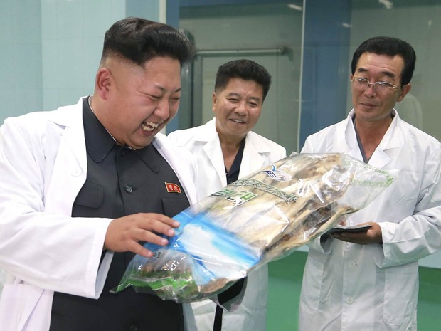 O ditador norte-coreano, Kim Jong-un, sorri com alimentos embalados à mão durante visita à fábrica de Kalma (Foto: Reuters/KCNA)