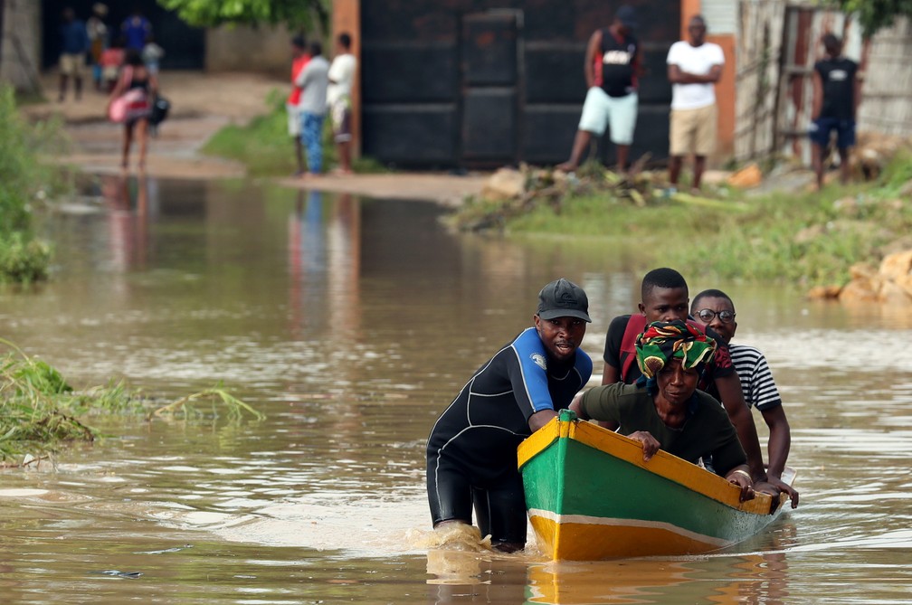Um homem conduz moradores através de uma via inundada em Pemba, Moçambique, nesta segunda (29). — Foto: Mike Hutchings/Reuters
