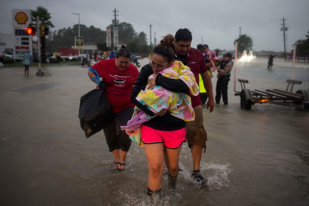 Família foge  de casa inundada após tempestade Harvey, em Houston, nos Estados Unidos, na segunda-feira (28)  (Foto: Adrees Latif/Reuters)