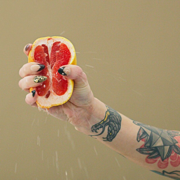 Studio shot of an unrecognizable woman squeezing a grapefruit slice against a brown background (Foto: Getty Images)