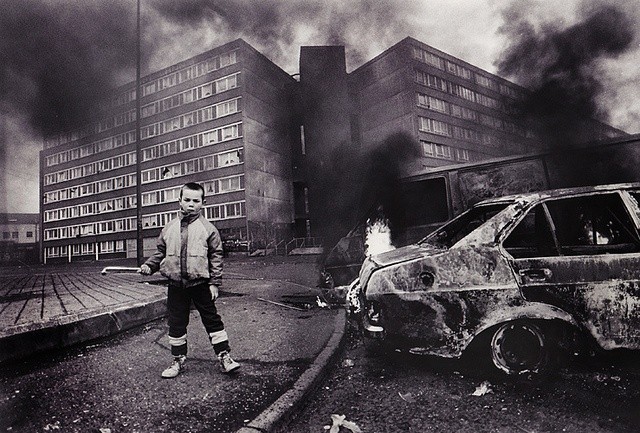 Belfast: Criança ao lado de carro queimado em área residencial durante conflitos