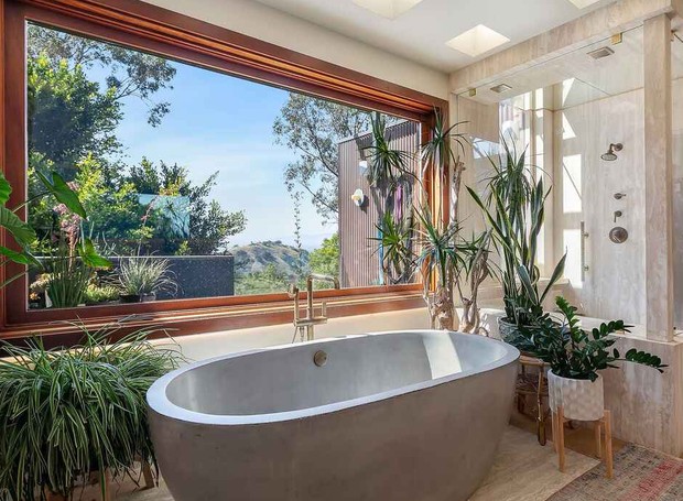 SUÍTE MASTER | O banheiro com formas orgânicas e muitas plantas dá continuidade para a estética do quarto (Foto: Reprodução / Realtor)