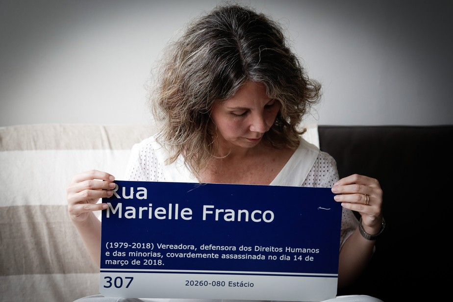 A jornalista Fernanda Chaves com uma placa em homenagem a Marielle Franco