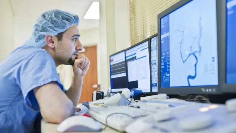 Médico analisa exames de paciente com aneurisma pelo computador (Foto: Getty Images via BBC)