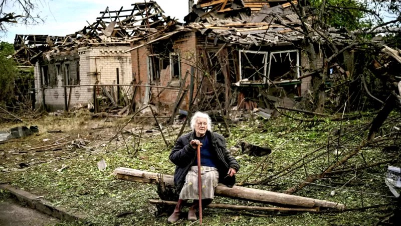 Uma mulher se senta em frente a duas casas que foram demolidas por um ataque de míssil, que matou outra mulher, em Druzhkivka, Donetsk (Foto: Getty Images via BBC News)