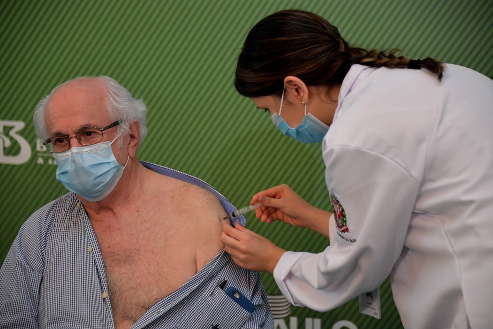 O médico Almir Ferreira de Andrade, de 79 anos, recebe a vacina CoronaVac contra a Covid-19 no Hospital das Clínicas, em São Paulo, neste domingo (17) — Foto: Nelson Almeida/AFP