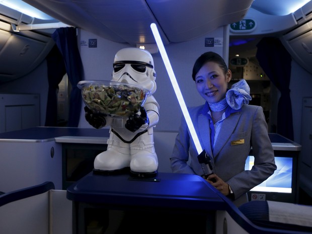 Comissária de bordo recebe visitantes com um sabre de luz (Foto: Edgar Su/Reuters)