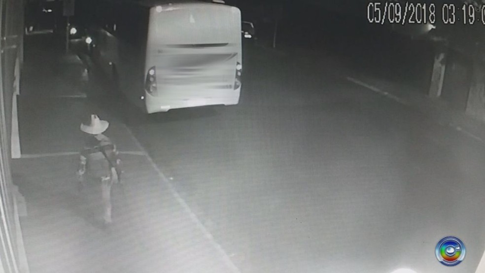 Um dos criminosos caminha pela calçada carregando uma arma (assalto quadrilha bauru bancos) — Foto: TV TEM / Reprodução 