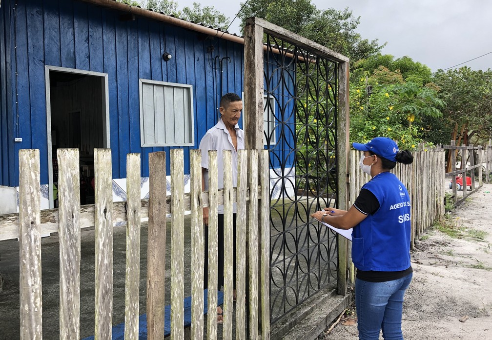 Agente de saúde visita a casa de comunitários orientando sobre cuidados com o coronavírus.  — Foto: Matheus Castro/G1