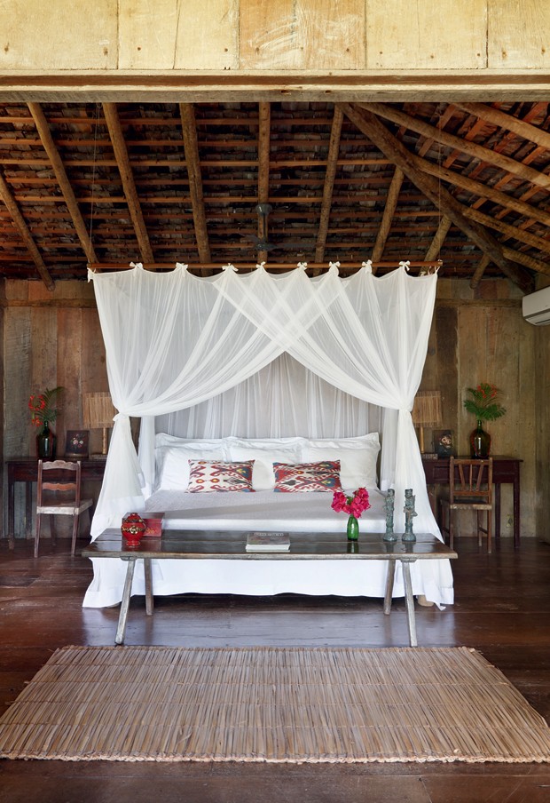 Suíte do chalé Madeira | O cortinado de filó sobre a cama realça os tons de palha e de madeira. Em frente a ela, esteira de palha (Foto: Evelyn Müller / Living Inside)