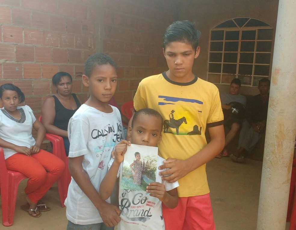 Irmãos de Ana Clara mostram foto da menina  (Foto: Juliana Peixoto/ G1)