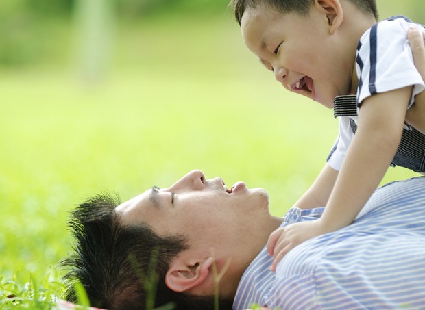 Pai brincando com filho na grama (Foto: Shutterstock)