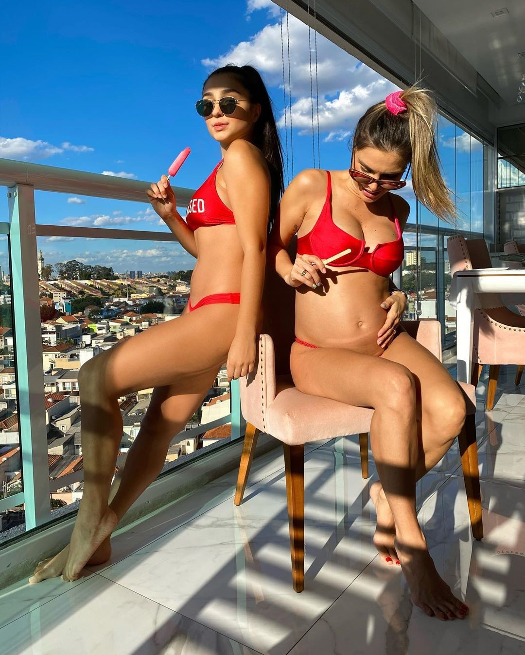 Flávia Viana and her daughter, Sabrina, sunbathe on a balcony