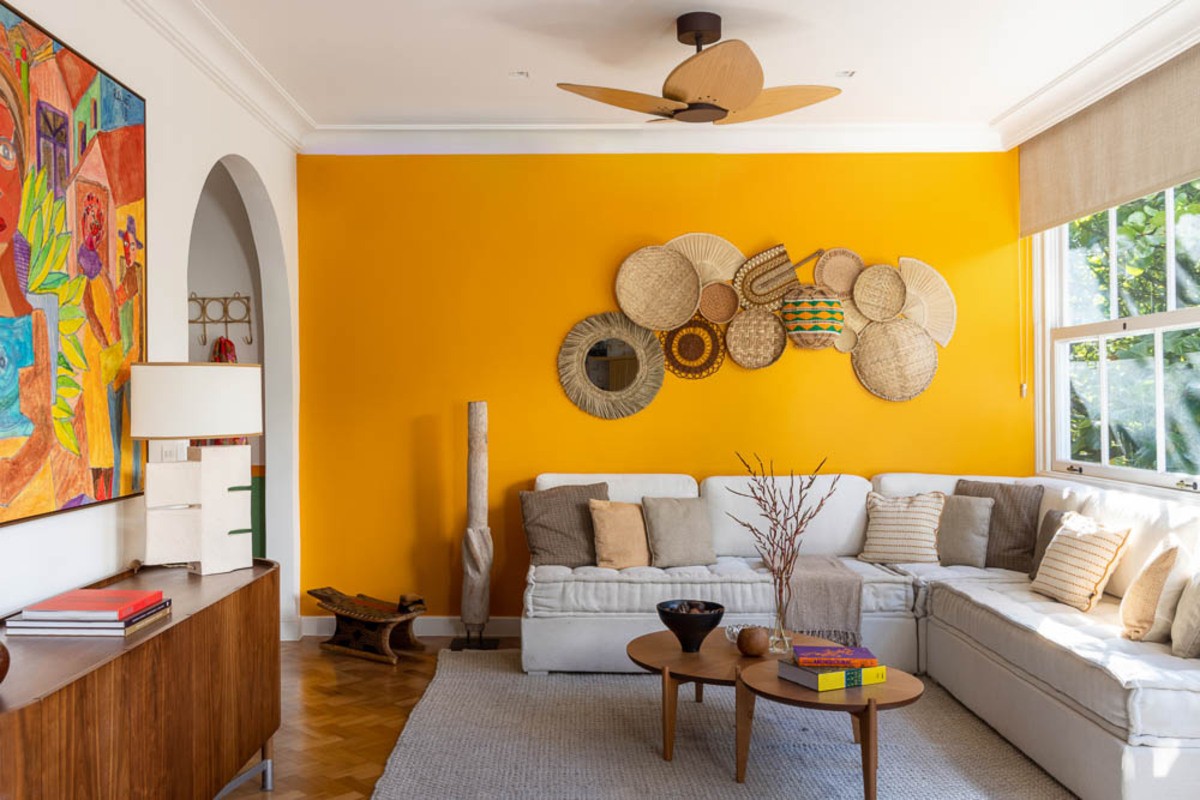 SALA | O sofá foi feito com tecidos da Ipanema Kravet. Na parede amarela, pratos de palha da Retrobel dão o tom no décor (Foto: André Nazareth / Divulgação)