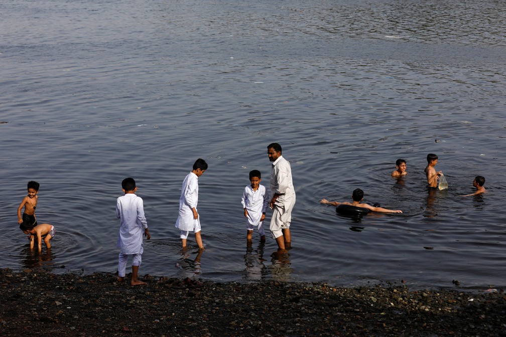 Paquistaneses tentam se refrescar em lago durante dia quente — Foto: Akhtar Soomro/REUTERS