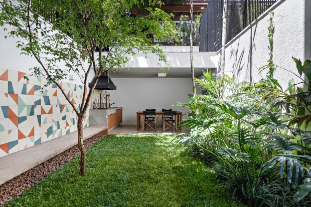 No pequeno jardim com paisagismo de Rodrigo Oliveira, o destaque é o banco de concreto que começa como bancada na cozinha e termina como churrasqueira na varanda gourmet (fundos) (Foto: Alessandro Guimarães / Divulgação)
