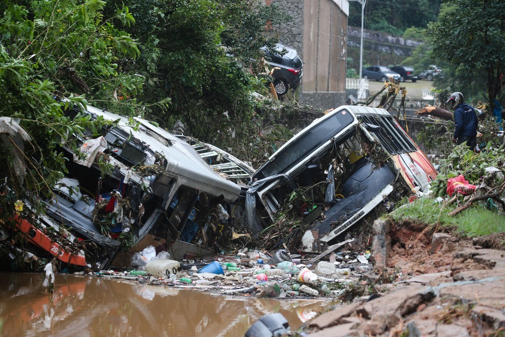 Um homem observa dois ônibus destruídos após temporal com deslizamentos em Petrópolis (RJ) — Foto: Ricardo Moraes/Reuters