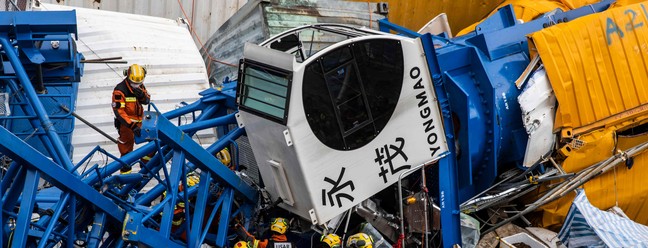 Equipe de busca e salvamento trabalha em um guindaste que caiu em Hong Kong, onde duas pessoas morreram e seis ficaram feridas em um canteiro de obras.  — Foto: ISAAC LAWRENCE / AFP