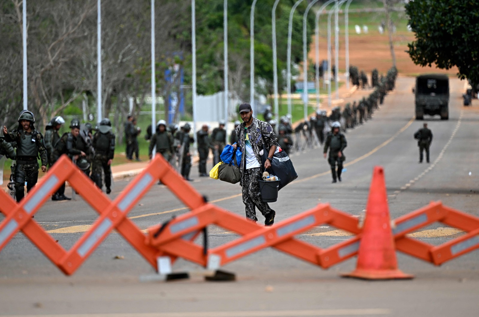 Manifestante carrega pertences enquanto deixa área onde bolsonaristas estavam acampados.  — Foto: Mauro Pimentel / AFP