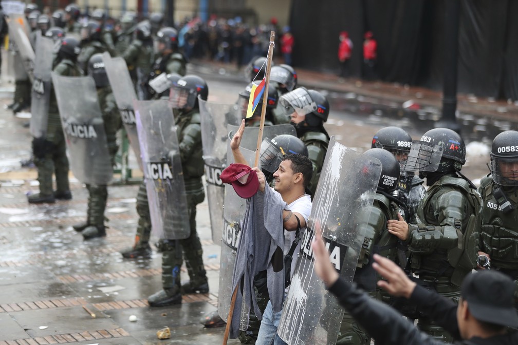 Homem tenta impedir que manifestantes joguem pedras contra a polícia durante uma greve nacional em Bogotá, na Colômbia, na quinta-feira (21). — Foto: Fernando Vergara/AP
