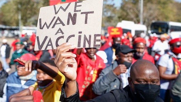 Em protesto na África do Sul, homem levanta cartaz com os dizeres 'Nós queremos vacina' (Foto: GETTY IMAGES via BBC NEWS)