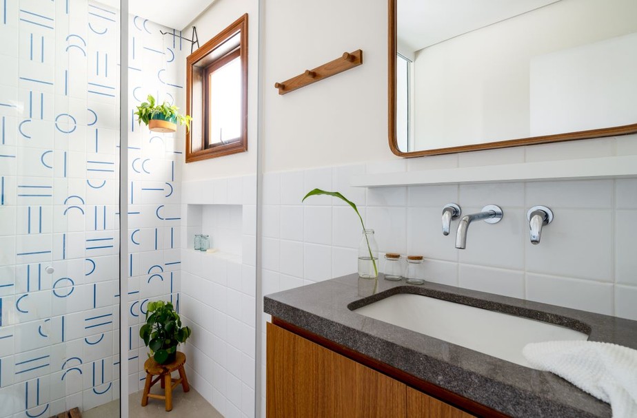 O banheiro projetado pelo escritório Arq. Simplifica é ornamentado com plantas, harmonizando as espécies com o azulejo e as estruturas de madeira do ambiente
