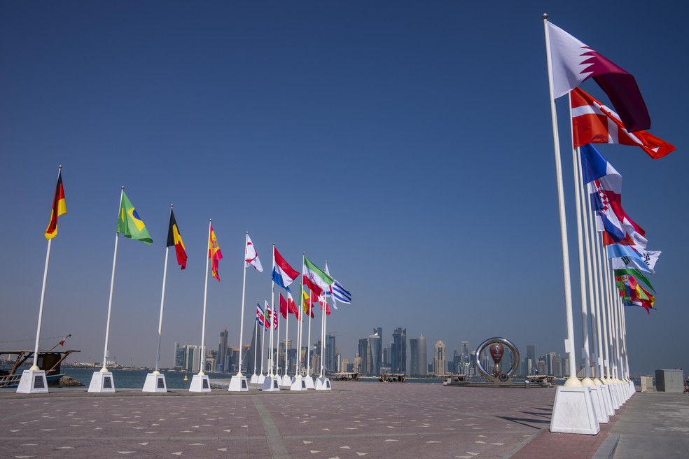 Bandeiras dos países que participarão da Copa do Mundo estão posicionadas em frente ao relógio oficial com a contagem regressiva para o início do evento, em Doha no Catar — Foto: Nariman El-Mofty/AP