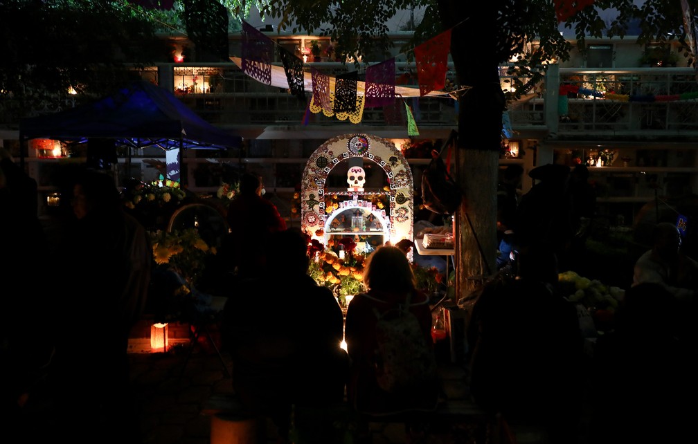 Pessoas fazem homenagens ao redor do túmulo de entes queridos no cemitério Los Reyes, na Cidade do México, durante as celebrações do Dia dos Mortos nesta sexta (1º) — Foto: Eduardo Verdugo/AP