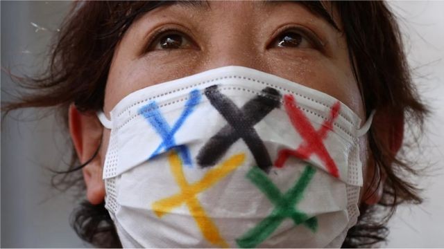 Torcedora usa máscara com o símbolo olímpico (Foto: EDGAR SU/REUTERS/GETTY IMAGES via BBC)