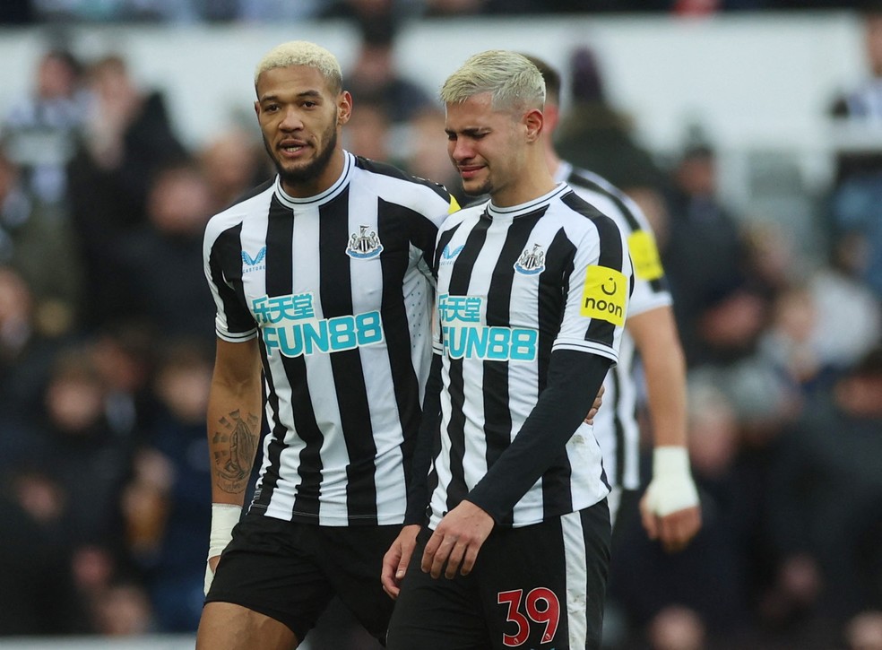 Bruno Guimarães deixa jogo do Newcastle chorando e consolado por Joelinton após lesão no tornozelo — Foto: Lee Smith/Reuters