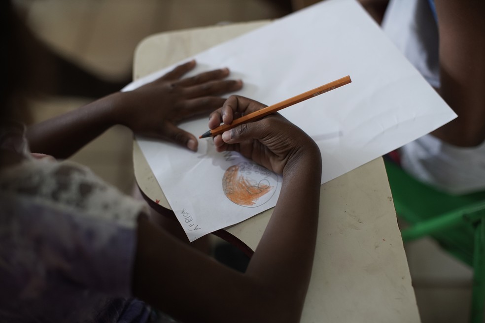 Foto mostra menina colorindo figura em uma biblioteca comunitária na favela do Morro do Salgueiro, no Rio de Janeiro, no dia 27 de agosto. — Foto: Silvia Izquierdo/AP